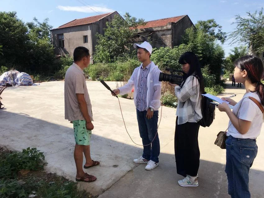 新闻记者在乡村进行采访与摄像